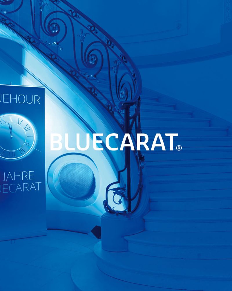 Bluecarat Logo vor blauem Hintergrund mit Rollup und Treppe auf einer Veranstaltung